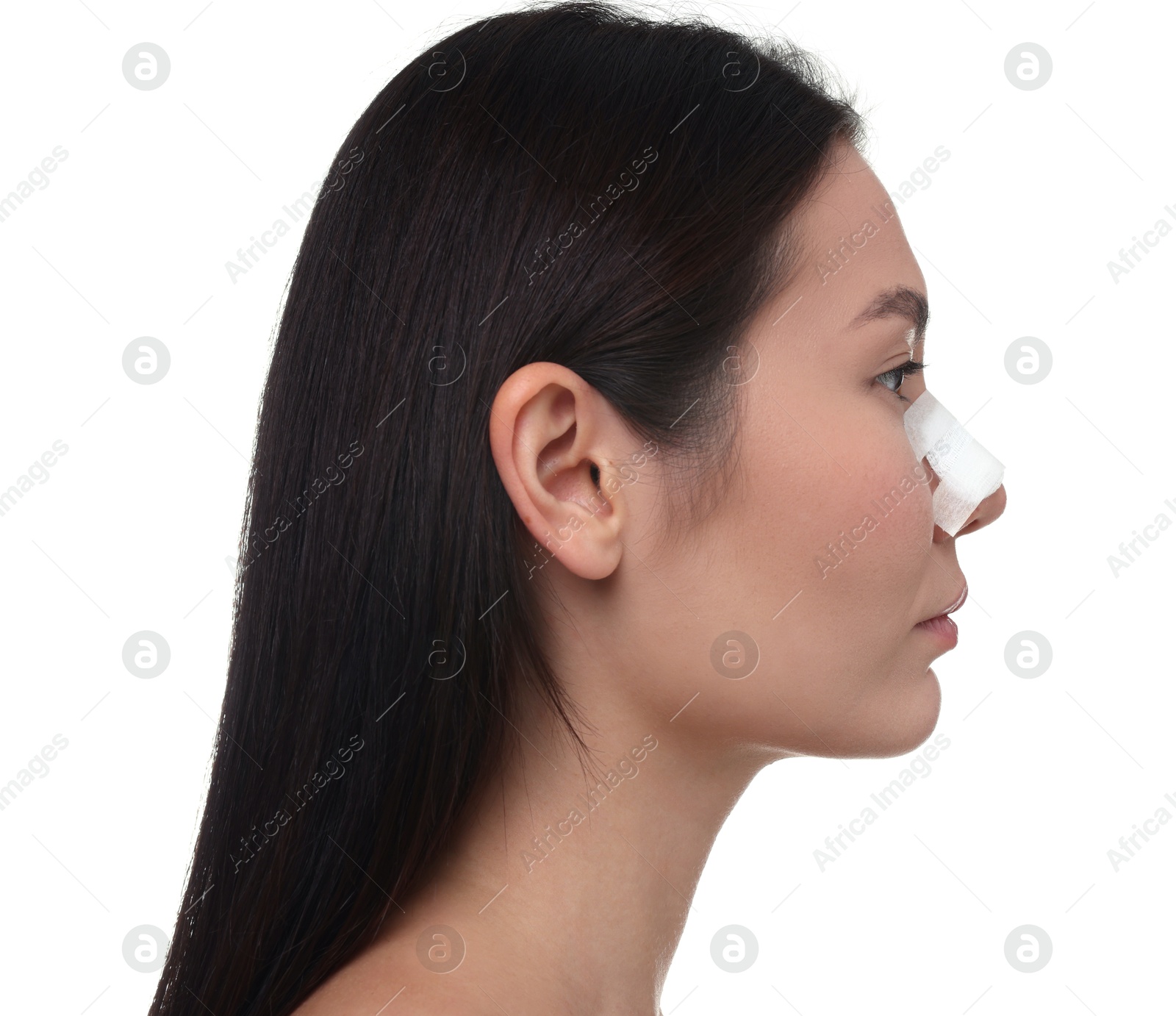 Photo of Woman with medical bandage on her nose after plastic surgery operation against white background, closeup