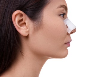 Photo of Woman with medical bandage on her nose after plastic surgery operation against white background, closeup