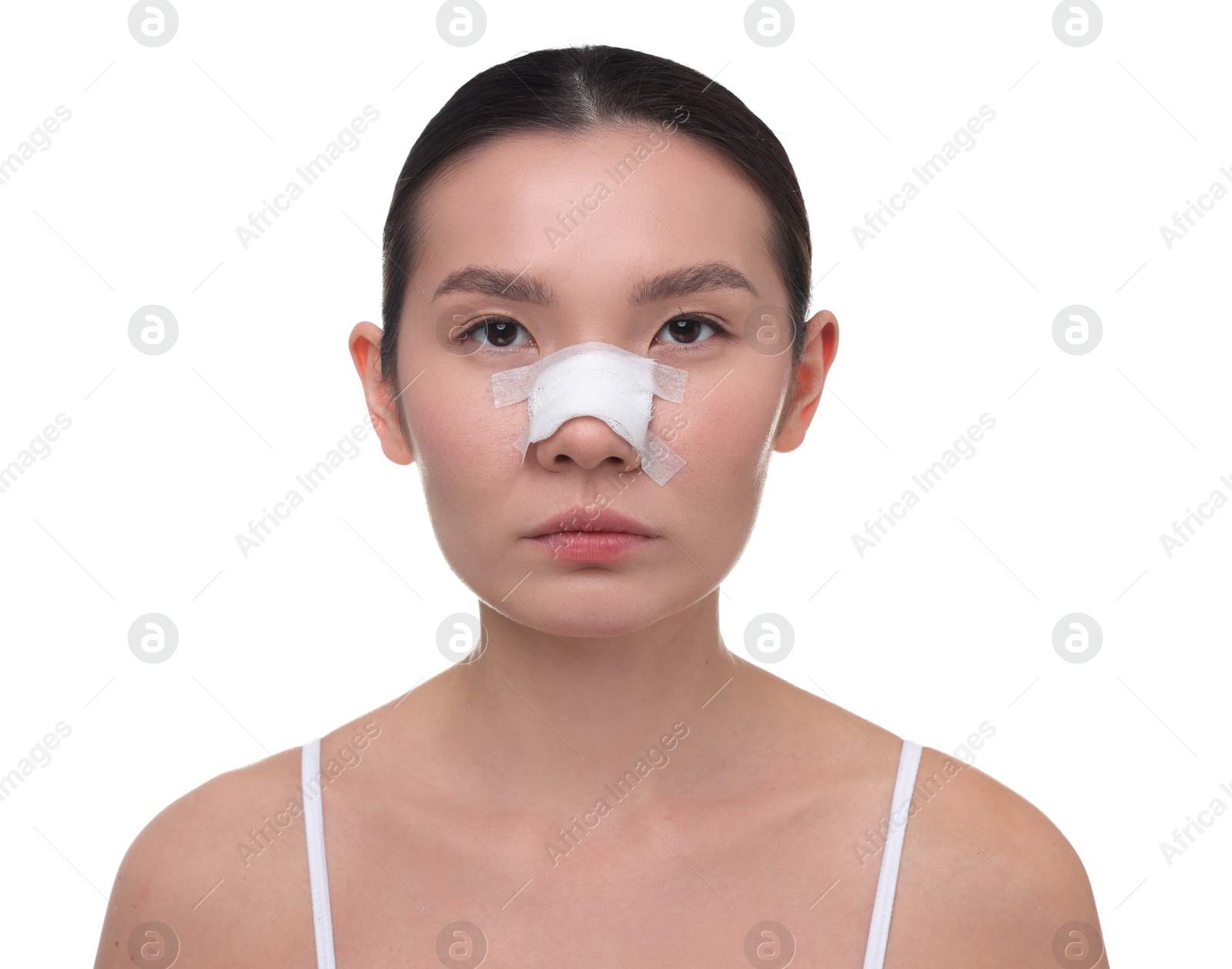 Photo of Woman with medical bandage on her nose after plastic surgery operation against white background