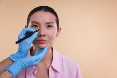 Photo of Doctor drawing marks on patient's nose for plastic surgery operation against beige background, closeup. Space for text