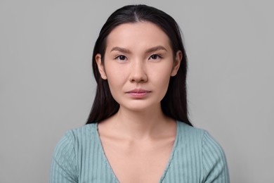 Woman with beautiful nose on light grey background. Rhinoplasty surgery