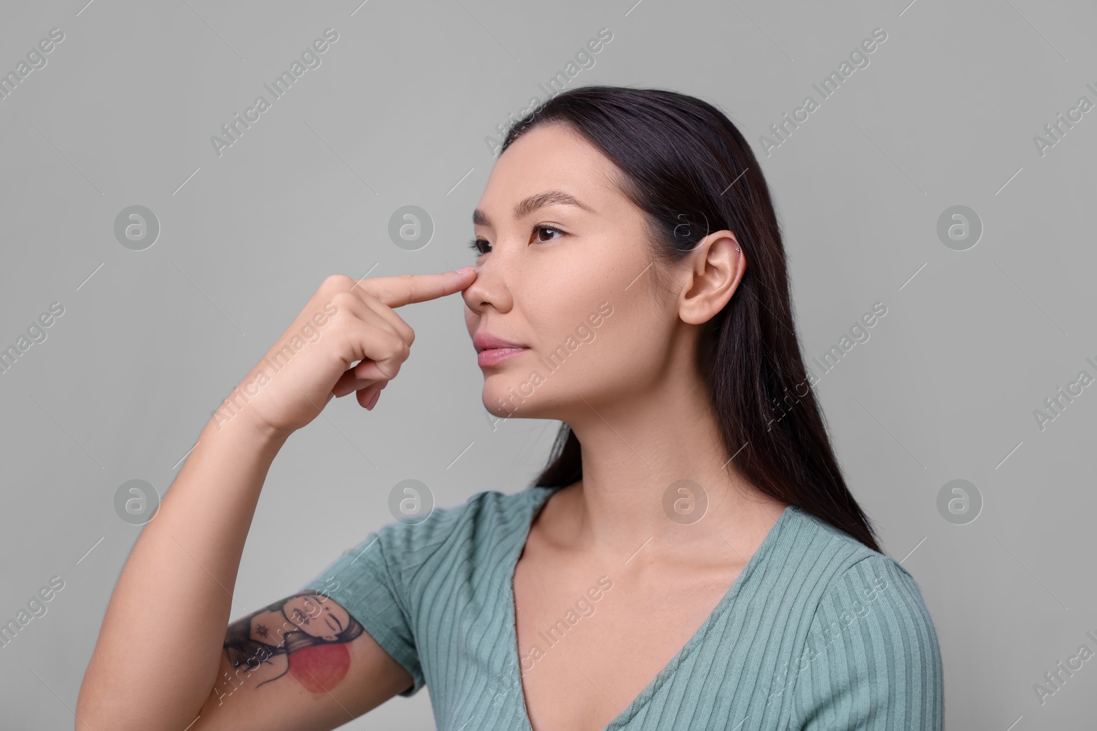 Photo of Woman touching her nose on light grey background