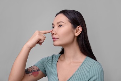 Photo of Woman touching her nose on light grey background