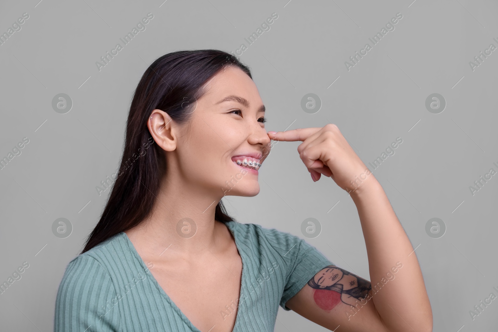 Photo of Woman touching her nose on light grey background