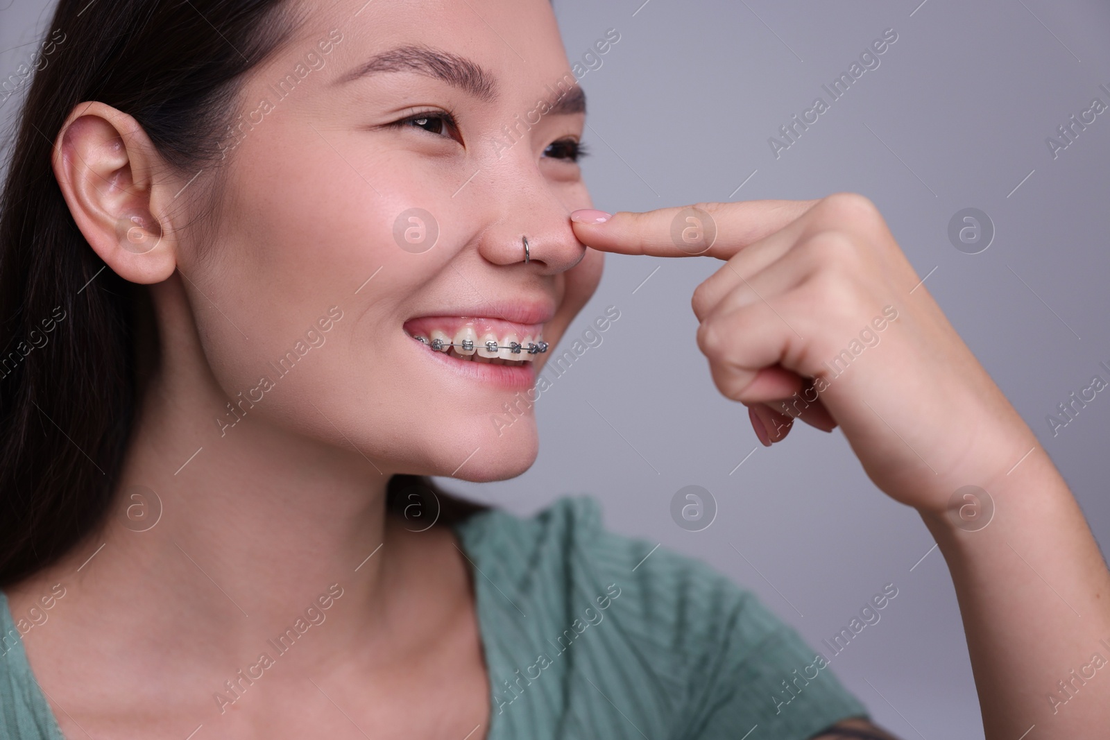 Photo of Woman touching her nose on light grey background, closeup