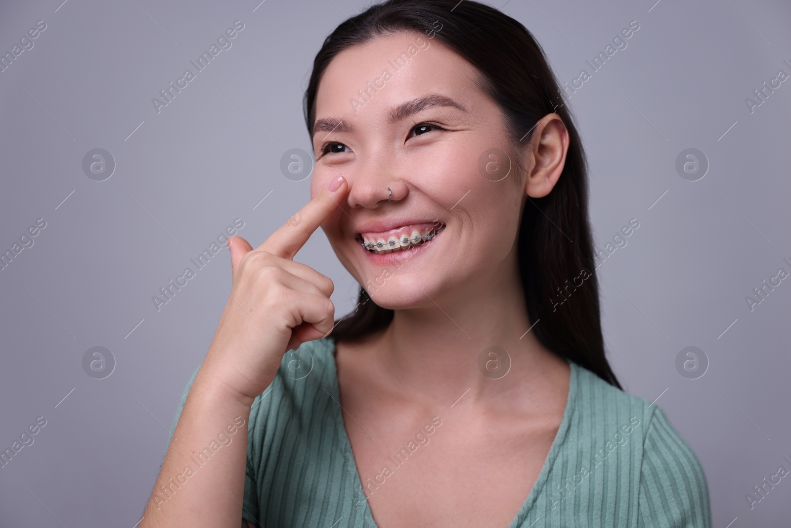 Photo of Woman touching her nose on light grey background