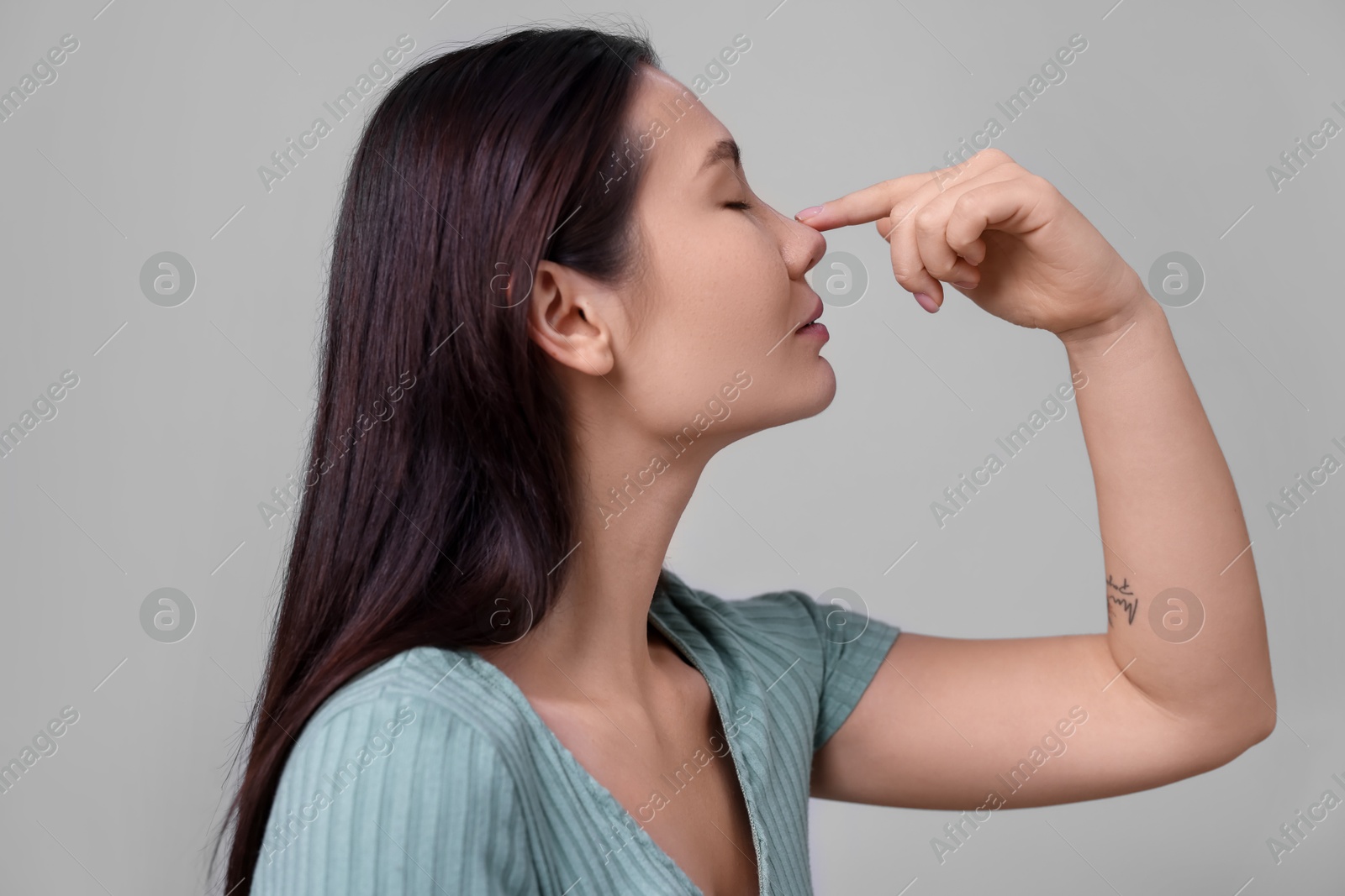 Photo of Woman touching her nose on light grey background