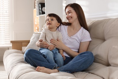 Happy mother with her cute little son on sofa at home