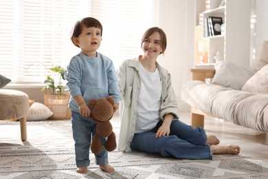 Photo of Happy mother and her cute little son with toy bear at home