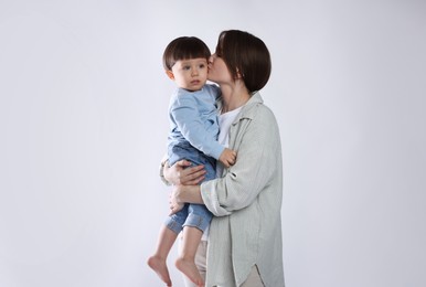 Photo of Beautiful mother with her cute little son on light grey background, space for text