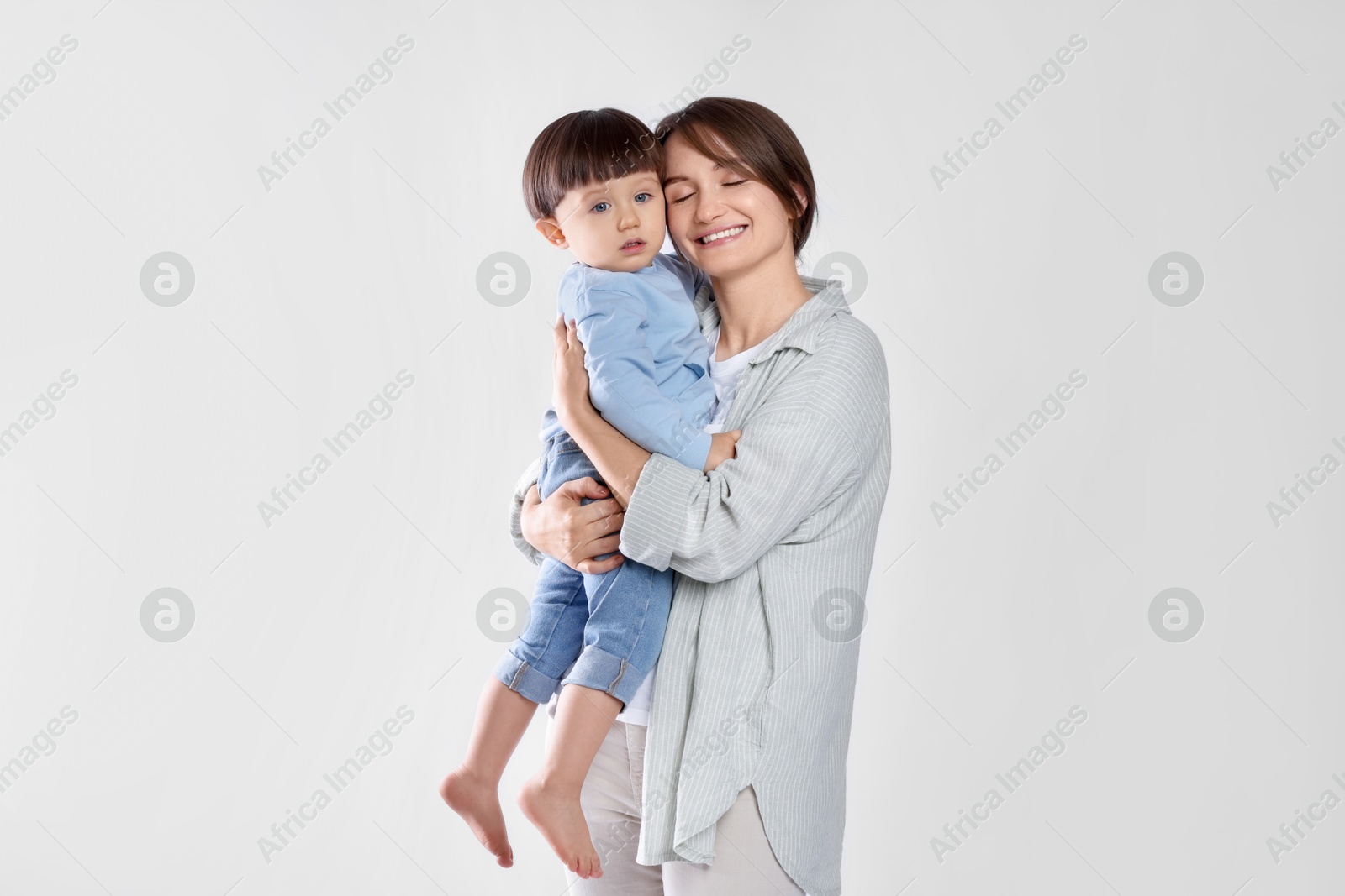 Photo of Beautiful mother with her cute little son on light grey background