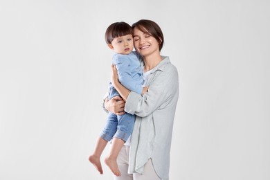 Photo of Beautiful mother with her cute little son on light grey background