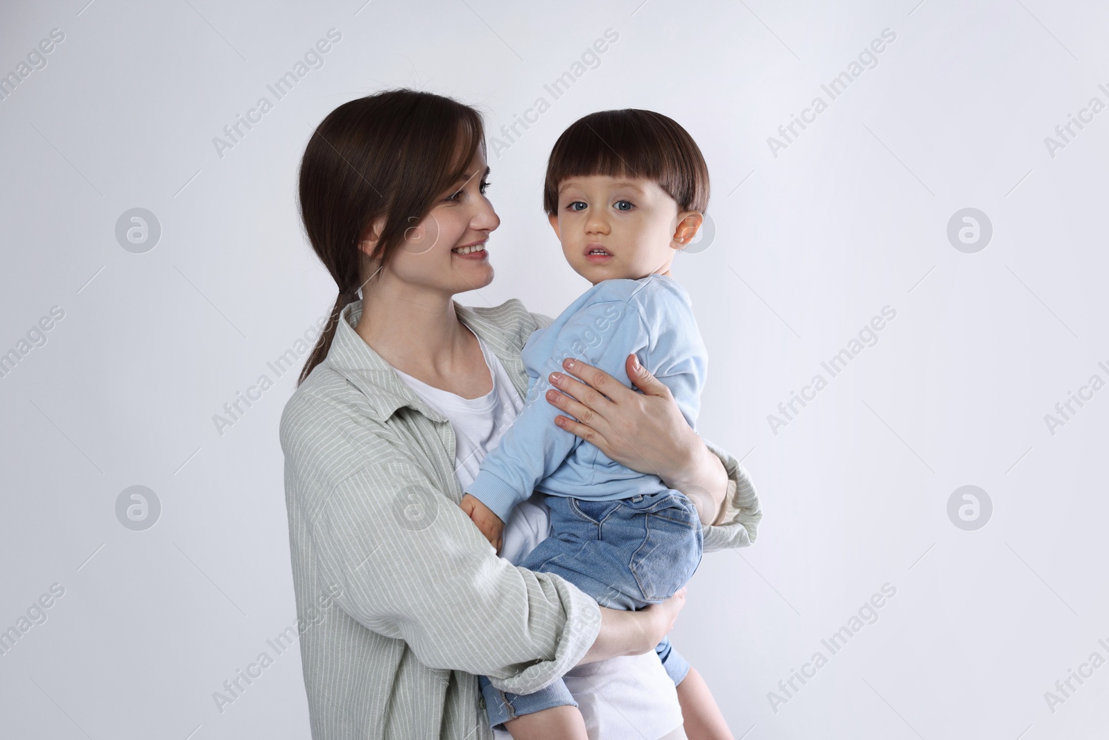 Photo of Beautiful mother with her cute little son on light grey background