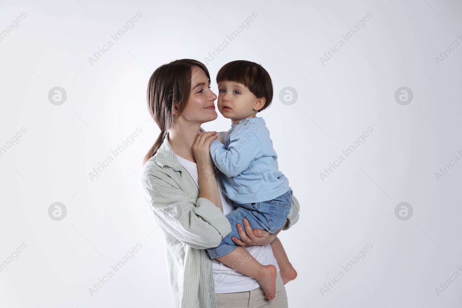 Photo of Beautiful mother with her cute little son on light grey background