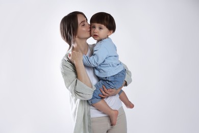 Photo of Beautiful mother with her cute little son on light grey background