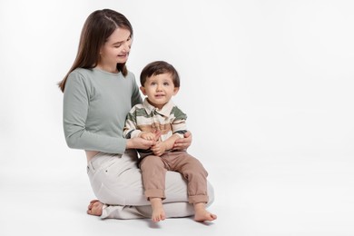 Photo of Happy mother with her cute little son on white background, space for text