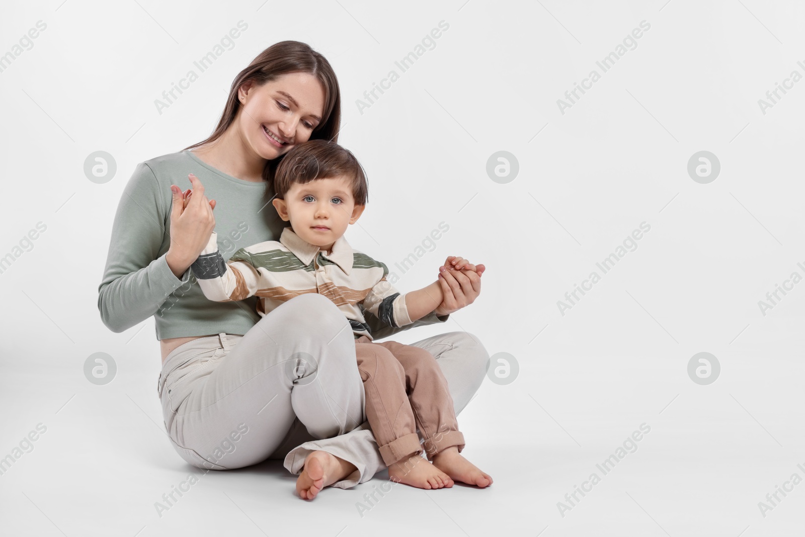 Photo of Happy mother with her cute little son on white background, space for text