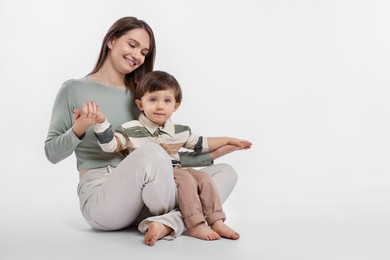 Photo of Happy mother with her cute little son on white background, space for text