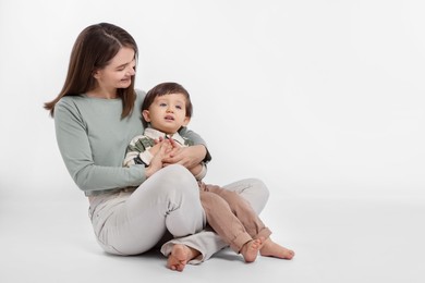 Photo of Happy mother with her cute little son on white background, space for text