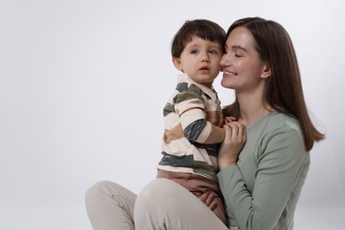 Photo of Happy mother with her cute little son on white background, space for text