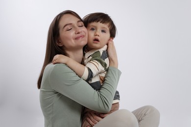 Photo of Beautiful mother with her cute little son on white background, space for text