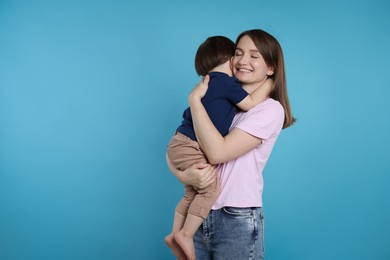 Photo of Happy mother with her cute little son on light blue background, space for text