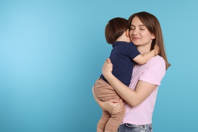 Photo of Beautiful mother with her cute little son on light blue background, space for text