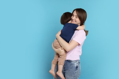 Photo of Happy mother with her cute little son on light blue background, space for text