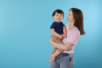 Photo of Happy mother with her cute little son on light blue background, space for text