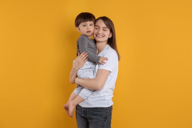 Photo of Happy mother with her cute little son on yellow background