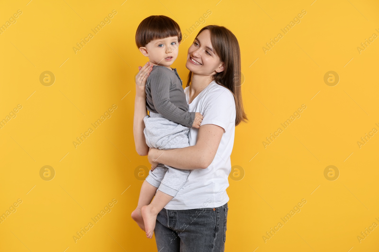 Photo of Happy mother with her cute little son on yellow background