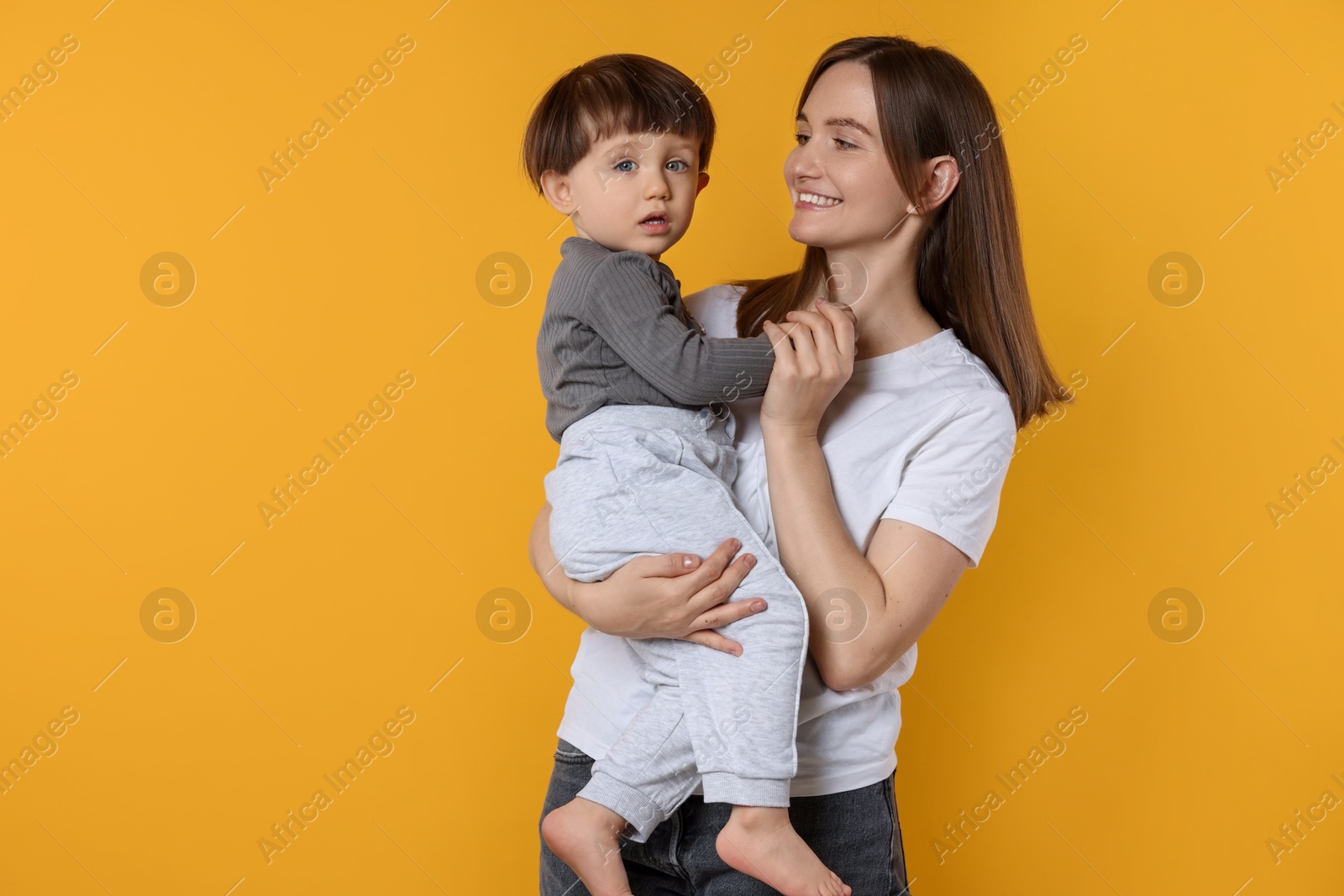 Photo of Happy mother with her cute little son on yellow background