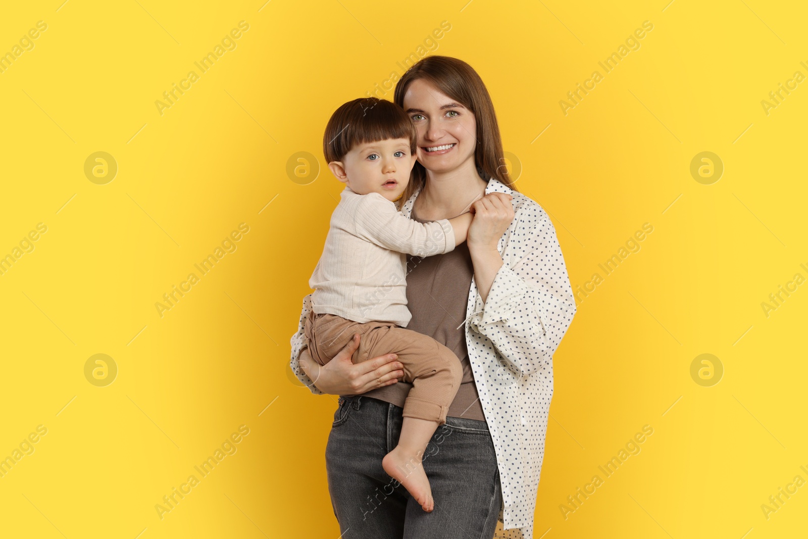 Photo of Happy mother with her cute little son on yellow background