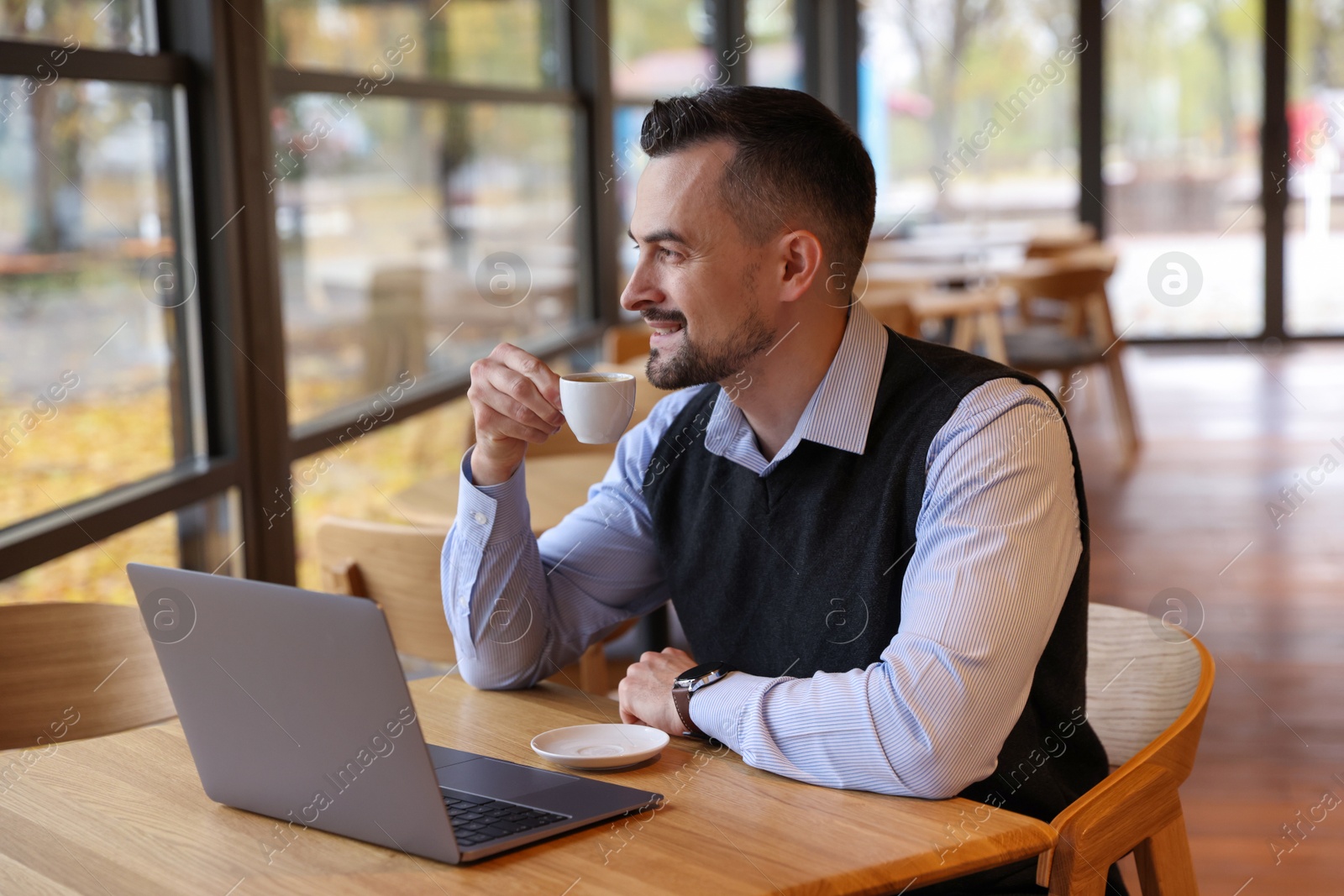 Photo of Man with cup of coffee working at table in cafe