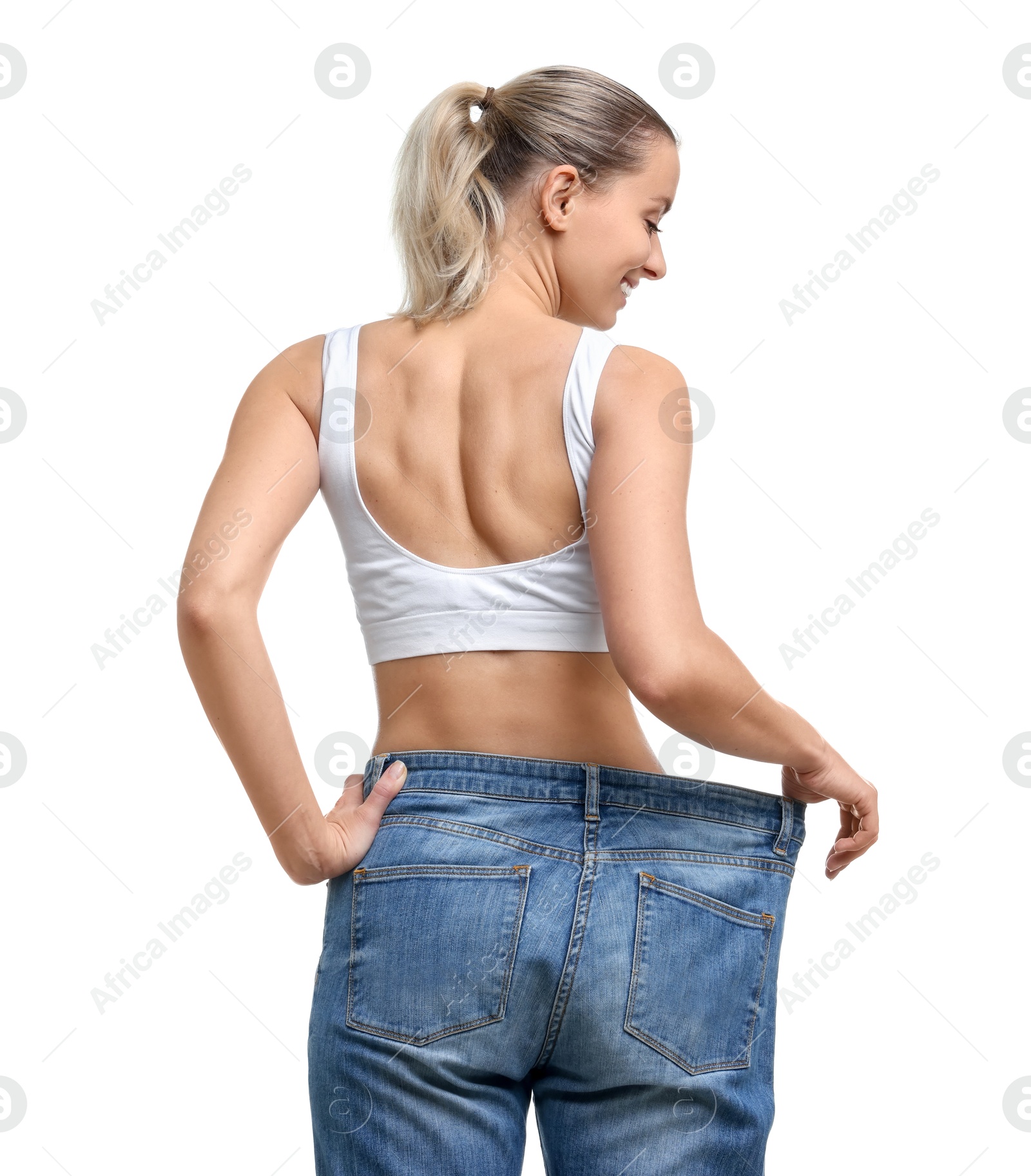 Photo of Weight loss. Happy woman wearing big jeans on white background