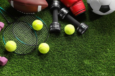 Photo of Different sports equipment on artificial grass, flat lay. Space for text