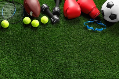 Photo of Different sports equipment on artificial grass, flat lay. Space for text