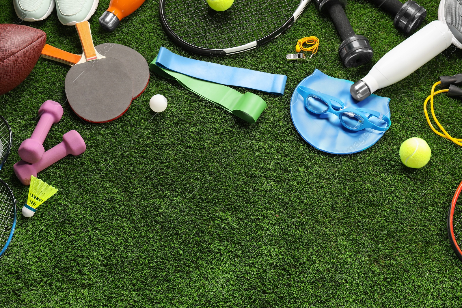 Photo of Different sports equipment on artificial grass, flat lay. Space for text