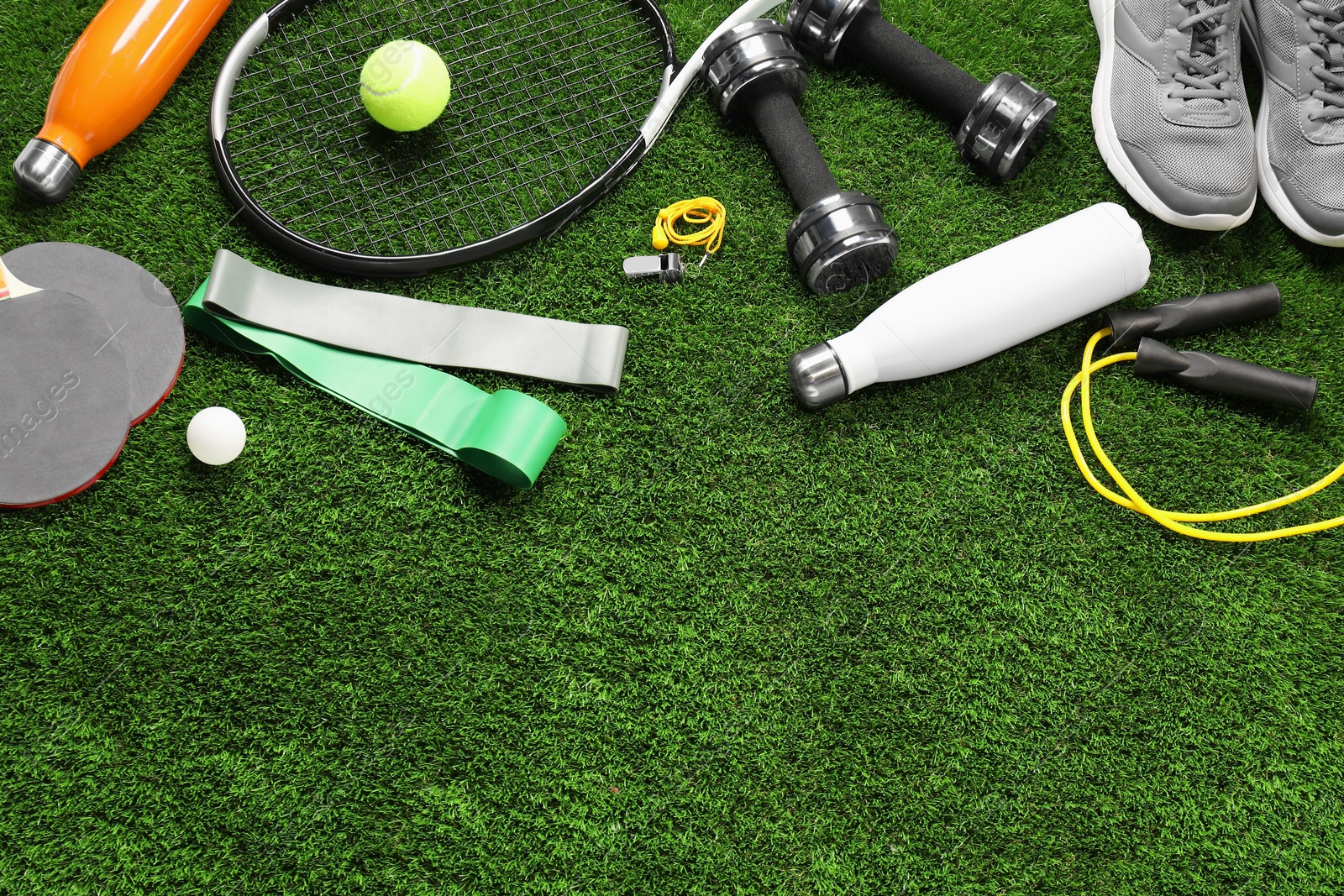 Photo of Different sports equipment on artificial grass, flat lay. Space for text