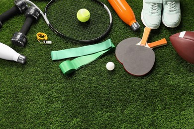 Photo of Different sports equipment on artificial grass, flat lay. Space for text