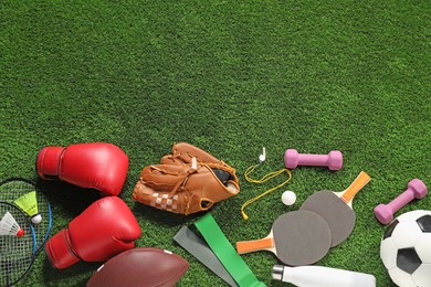 Photo of Different sports equipment on artificial grass, flat lay. Space for text