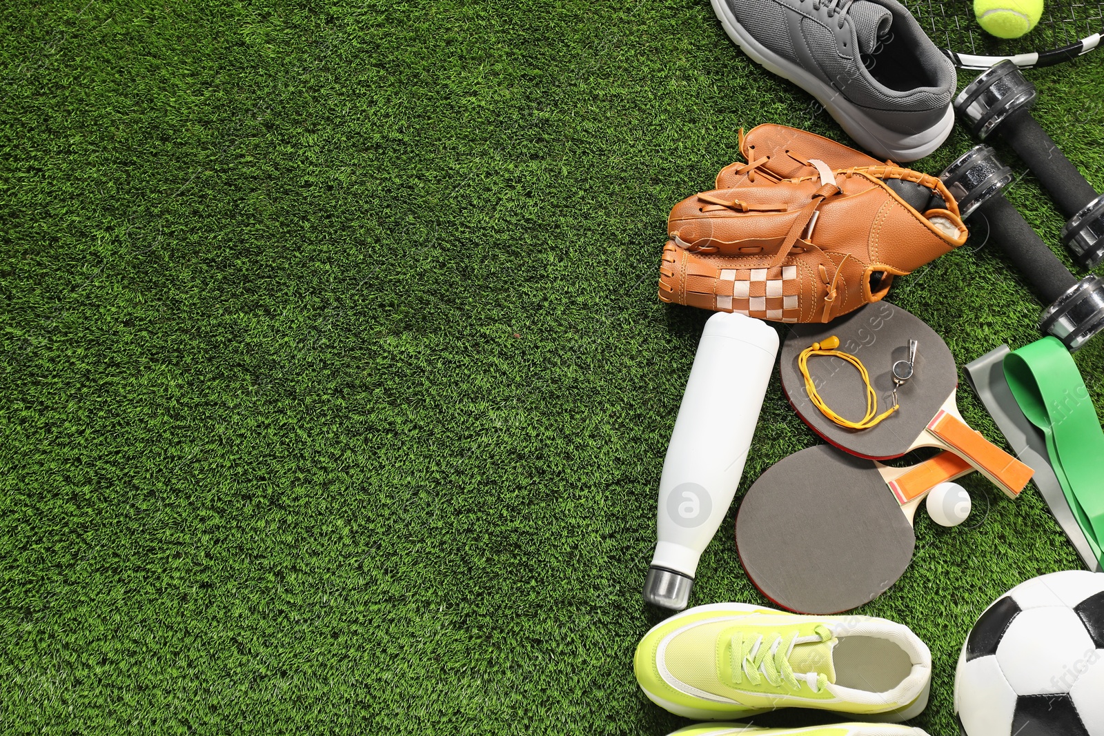 Photo of Different sports equipment on artificial grass, flat lay. Space for text