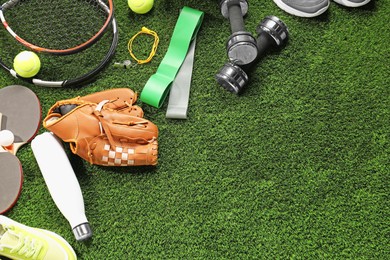 Photo of Different sports equipment on artificial grass, flat lay. Space for text