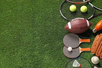 Photo of Different sports equipment on artificial grass, flat lay. Space for text