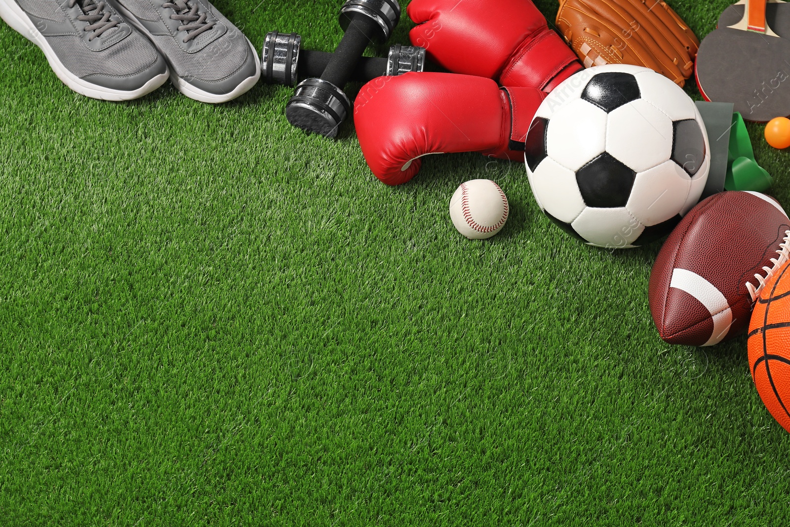 Photo of Different sport equipment on artificial grass, above view. Space for text