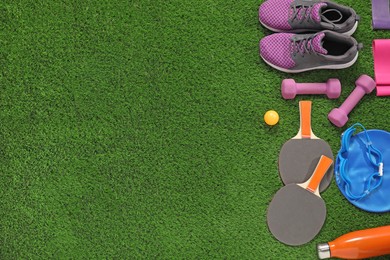 Photo of Different sport equipment on artificial grass, flat lay. Space for text