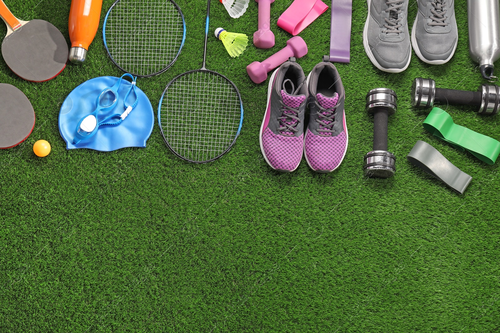 Photo of Different sport equipment on artificial grass, flat lay. Space for text