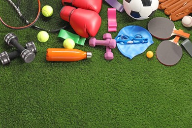 Photo of Different sport equipment on artificial grass, flat lay. Space for text