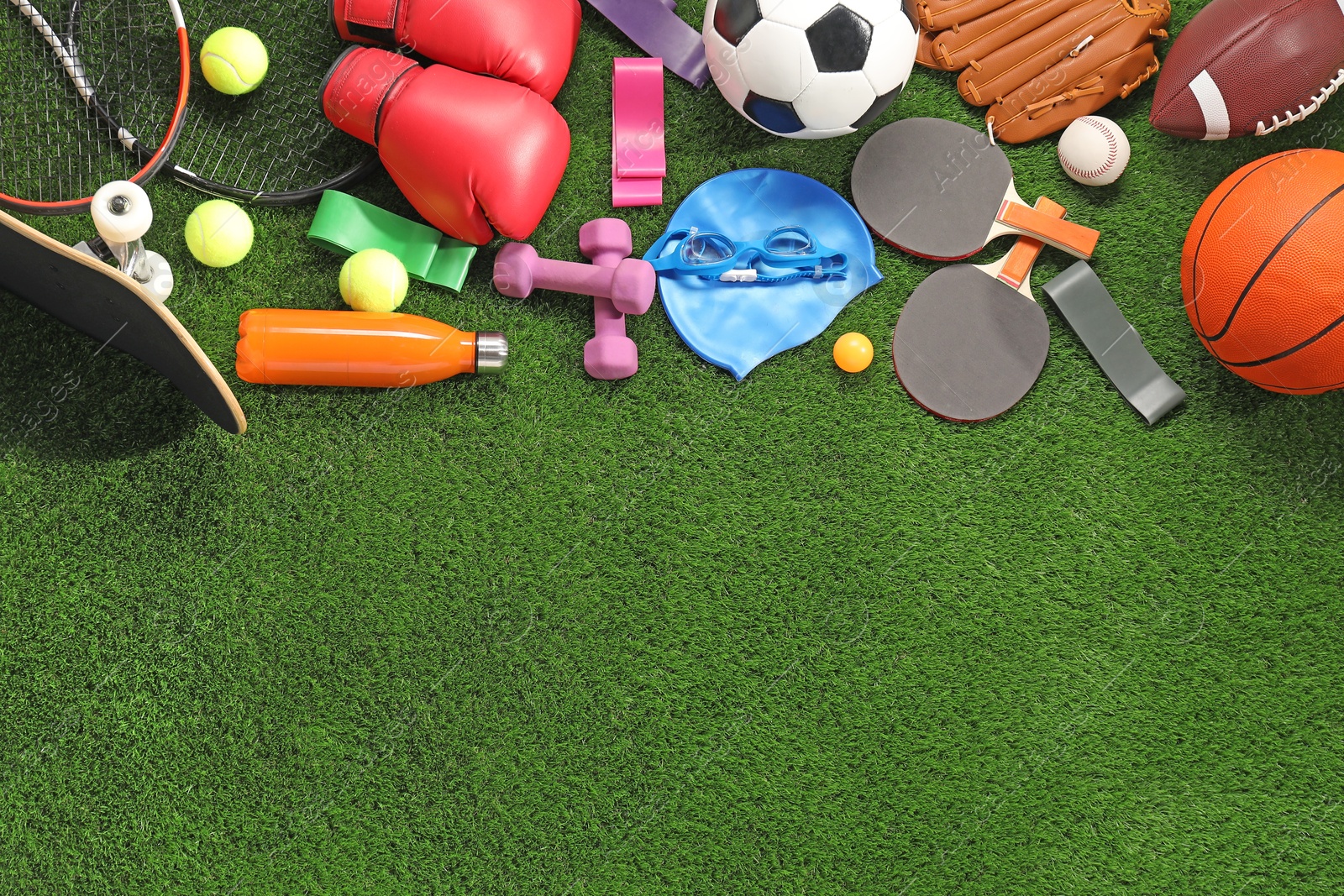 Photo of Different sport equipment on artificial grass, flat lay. Space for text