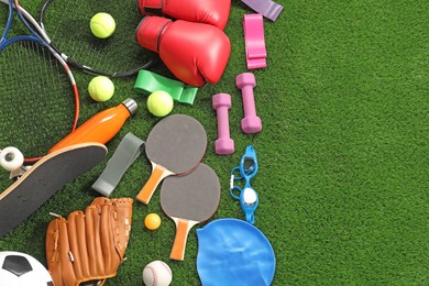 Photo of Different sport equipment on artificial grass, flat lay. Space for text